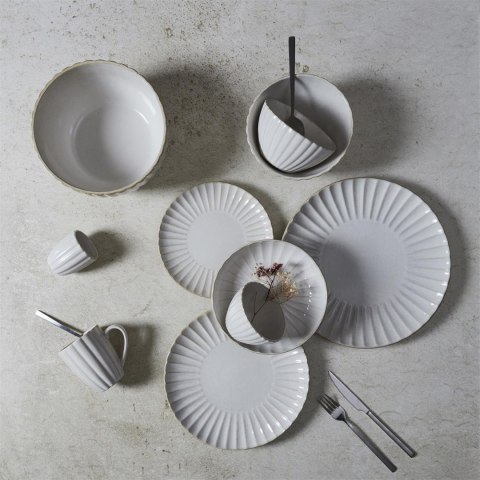 Rozłożona na jasnym blacie ryflowana beżowa zastawa ceramiczna z talerzami, miskami i kubkami, widok z góry.