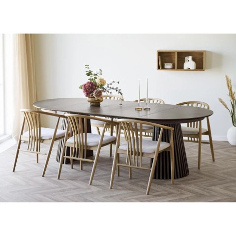 Rozłożony owalny stół z dymionego dębu Osaka IV z krzesłami w jasnej jadalni z zastawą i wazonem na blacie.