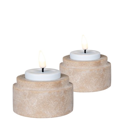 Dwa trawertynowe świeczniki Seisei z zapalonymi białymi świeczkami typu tealight na białym tle.