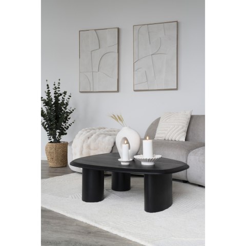 Ceramiczny wazon Iwaku na czarnym stoliku kawowym przy szarej kanapie w jasnym salonie.