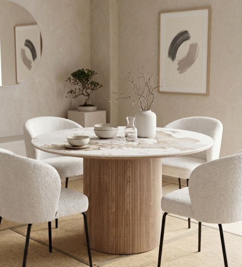 Okrągły stół Seramikkusu z białymi krzesłami boucle w jadalni, obok drzewka bonsai i minimalistycznego obrazu.